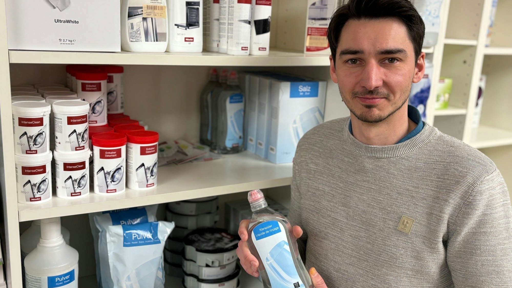 Auf dem Bild ist ein Mann zu sehen, der ein Pflegeprodukt für Spülmaschinen hält.