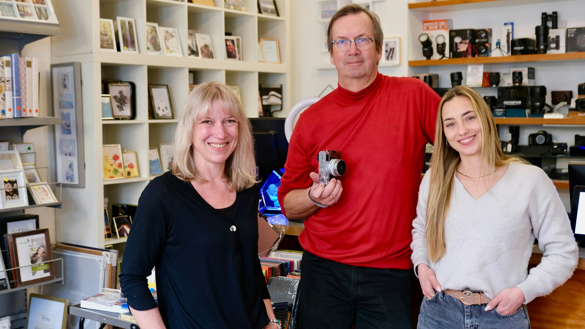 Drei Personen stehen in einem Fotoladen