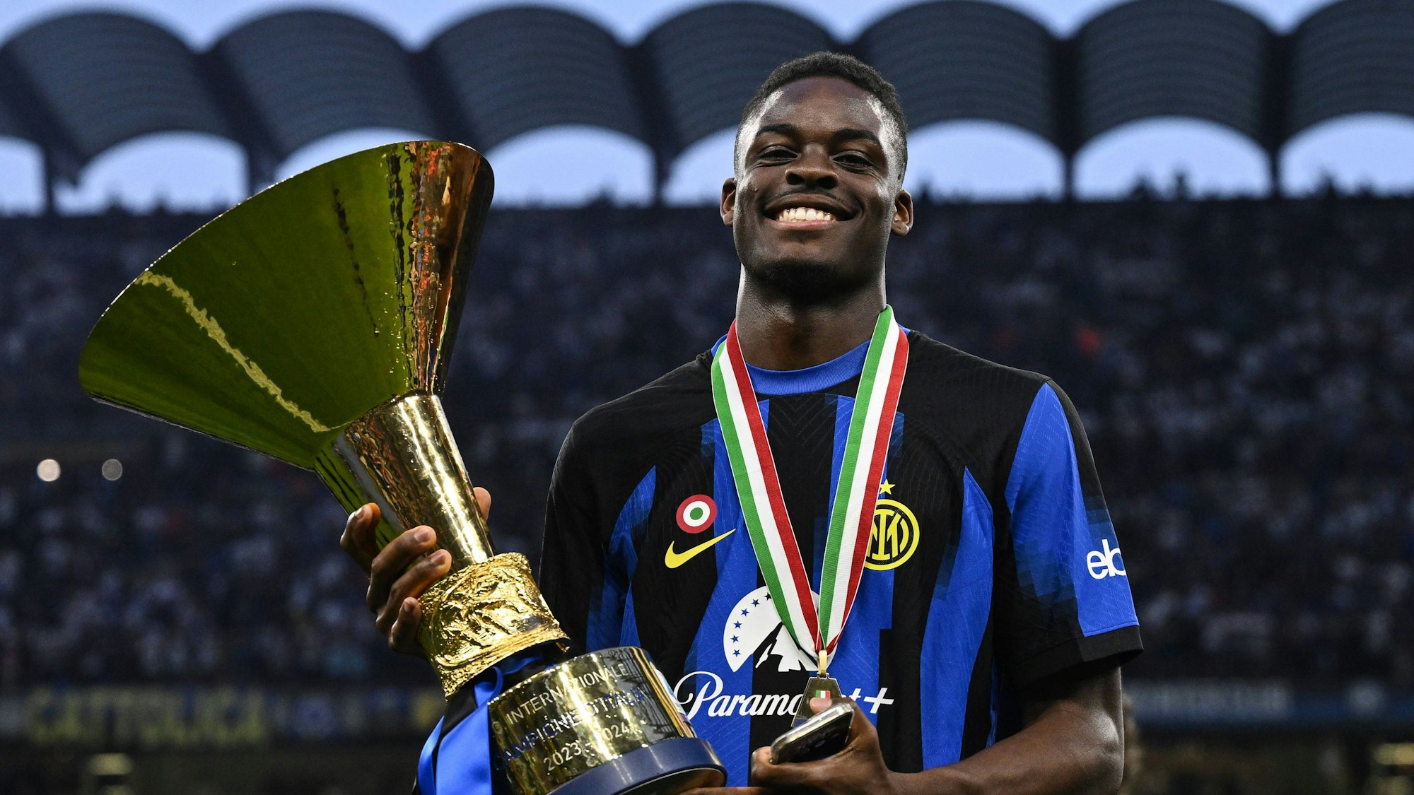 Ein Fußballspieler hält einen Pokal in den Händen.