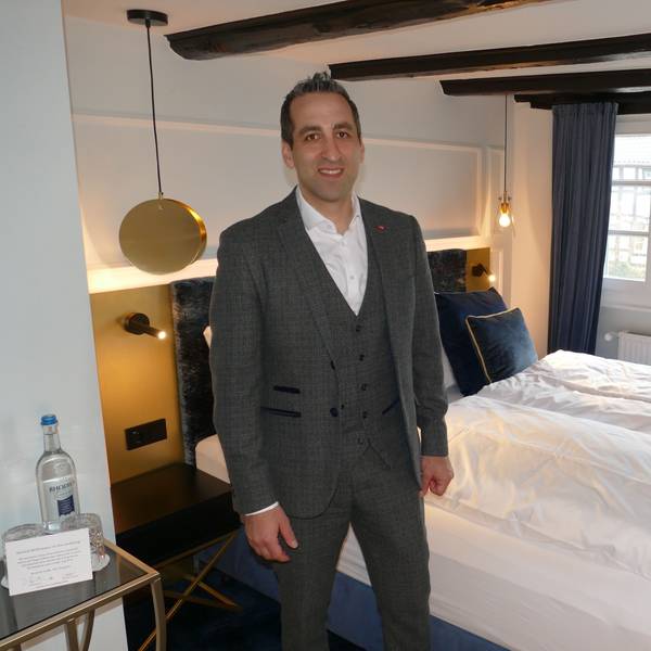 Ein Mann steht in einem Hotelzimmer vor dem Bett.