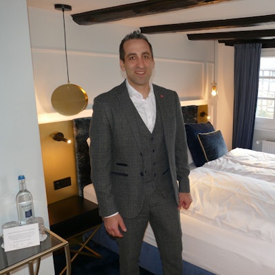 Ein Mann steht in einem Hotelzimmer vor dem Bett.