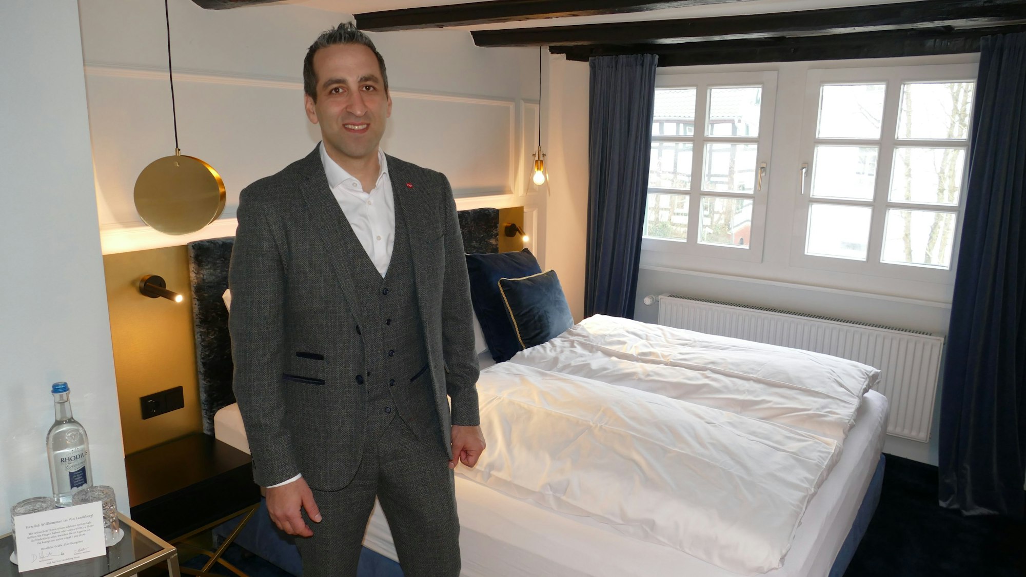 Ein Mann steht in einem Hotelzimmer vor dem Bett.