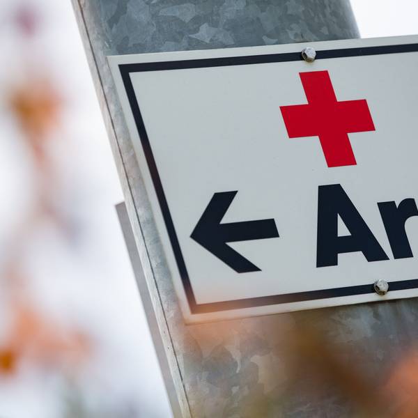 Ein Schild mit der Aufschrift „Arzt“ hängt an einer Straßenlaterne.