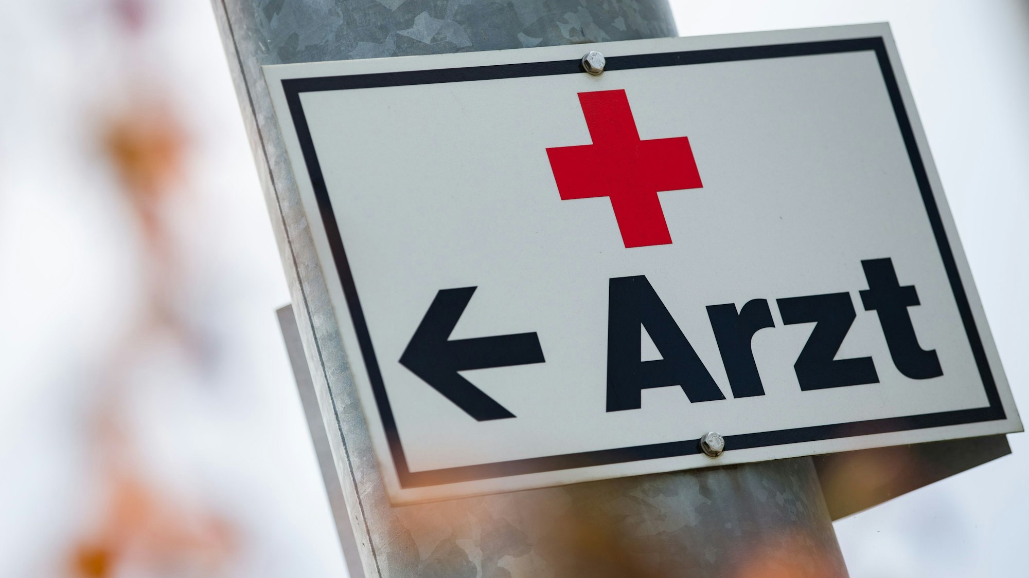 Ein Schild mit der Aufschrift „Arzt“ hängt an einer Straßenlaterne.