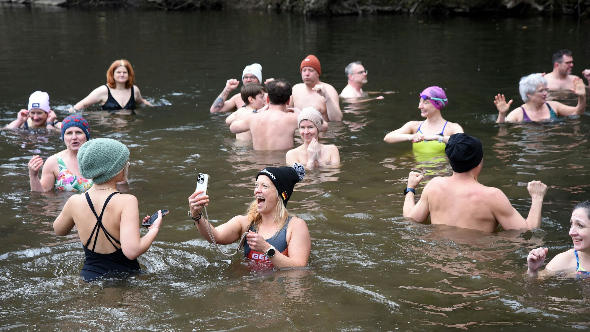 Eine Gruppe Schwimmer beim Eisbaden in der Agger. Eine Frau macht ein Selfie von sich.