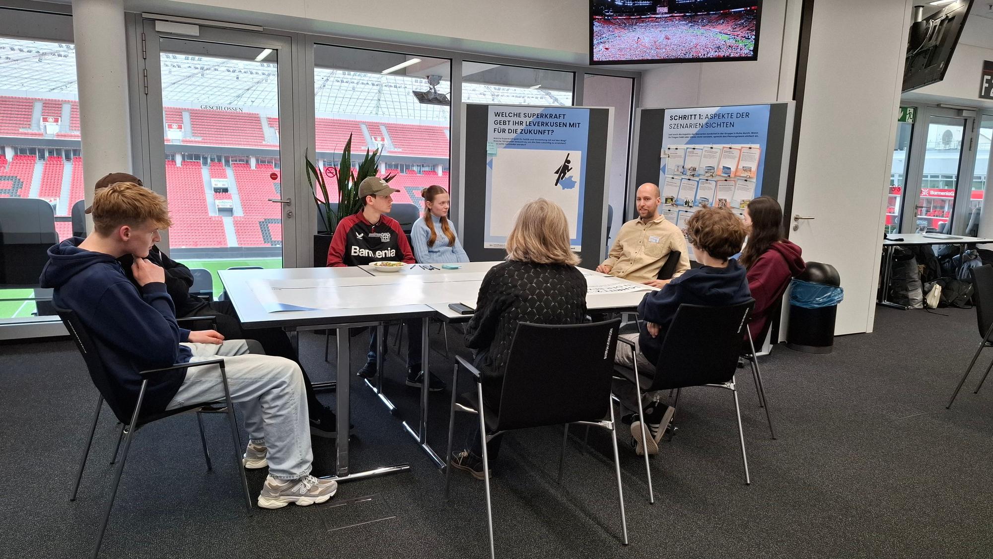 Junge Leute sitzen an einem Tisch in der Bayarena.