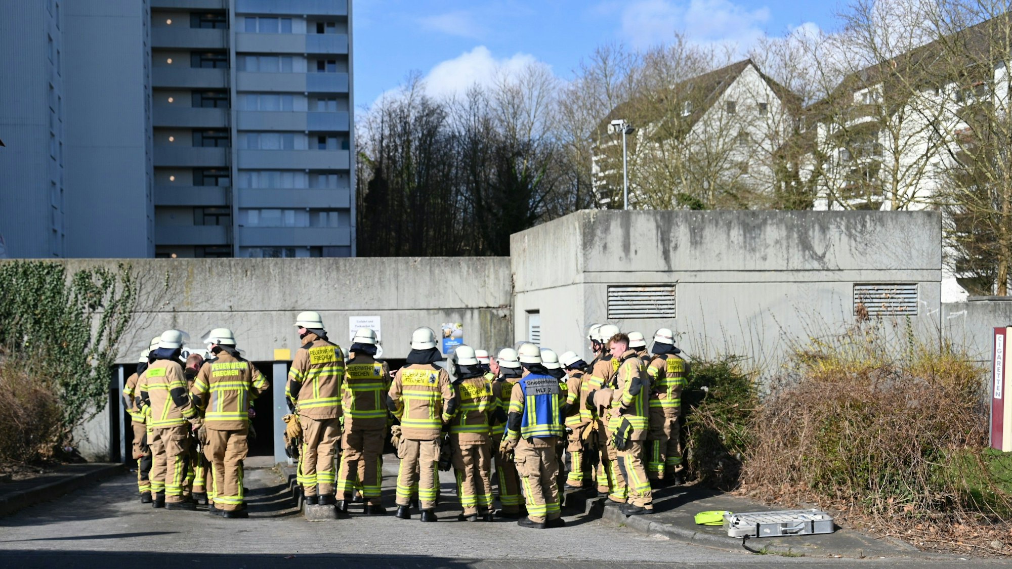 Feuerwehrleute stehen vor der Einfahrt zur Tiefgarage.