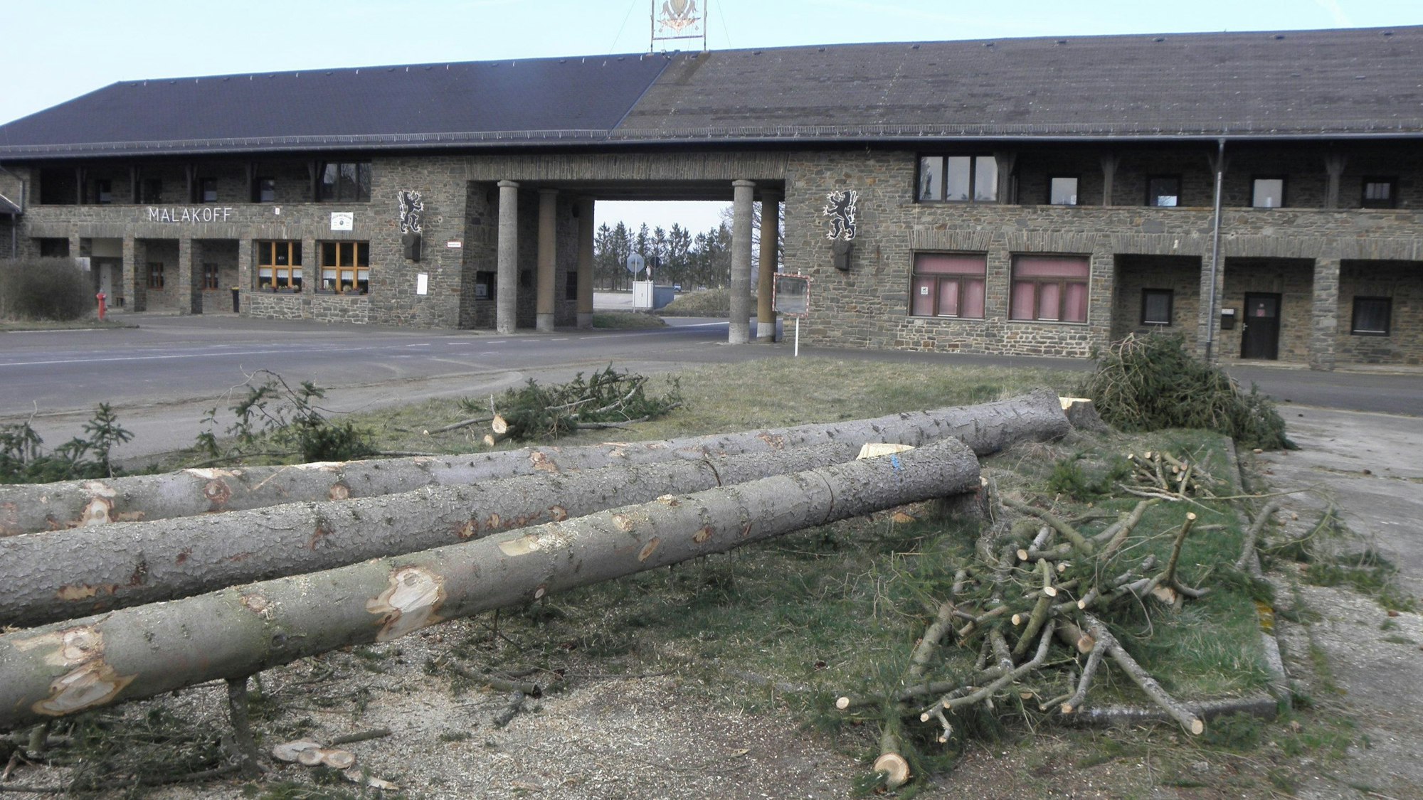 Das Bild zeigt das Malakoff-Gebäude, davor liegen gefällte Bäume.