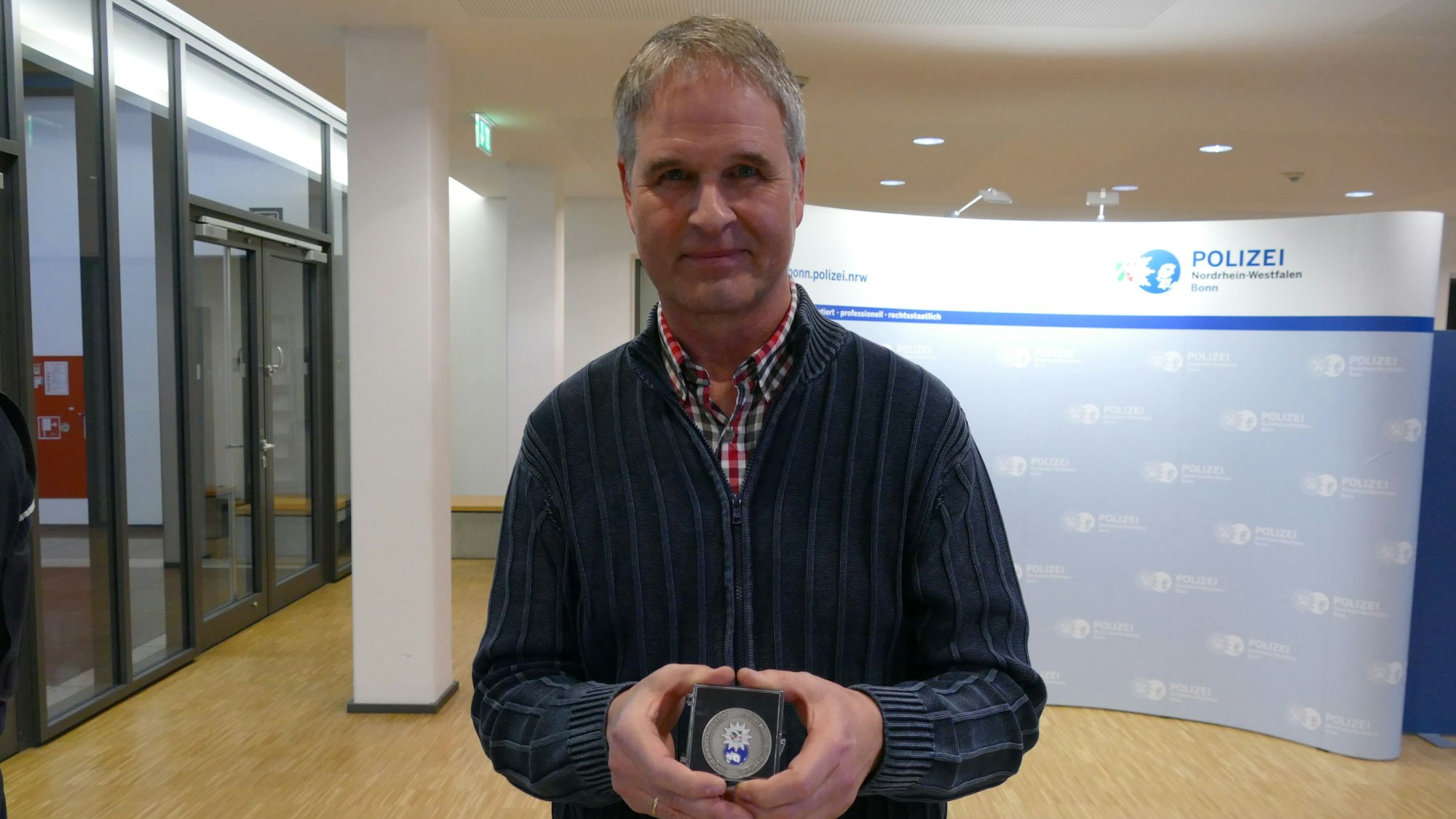 Reinhard van Helden zeigt seine Medaille, die er erhielt, weil er einen Taschendiebstahl verhinderte.