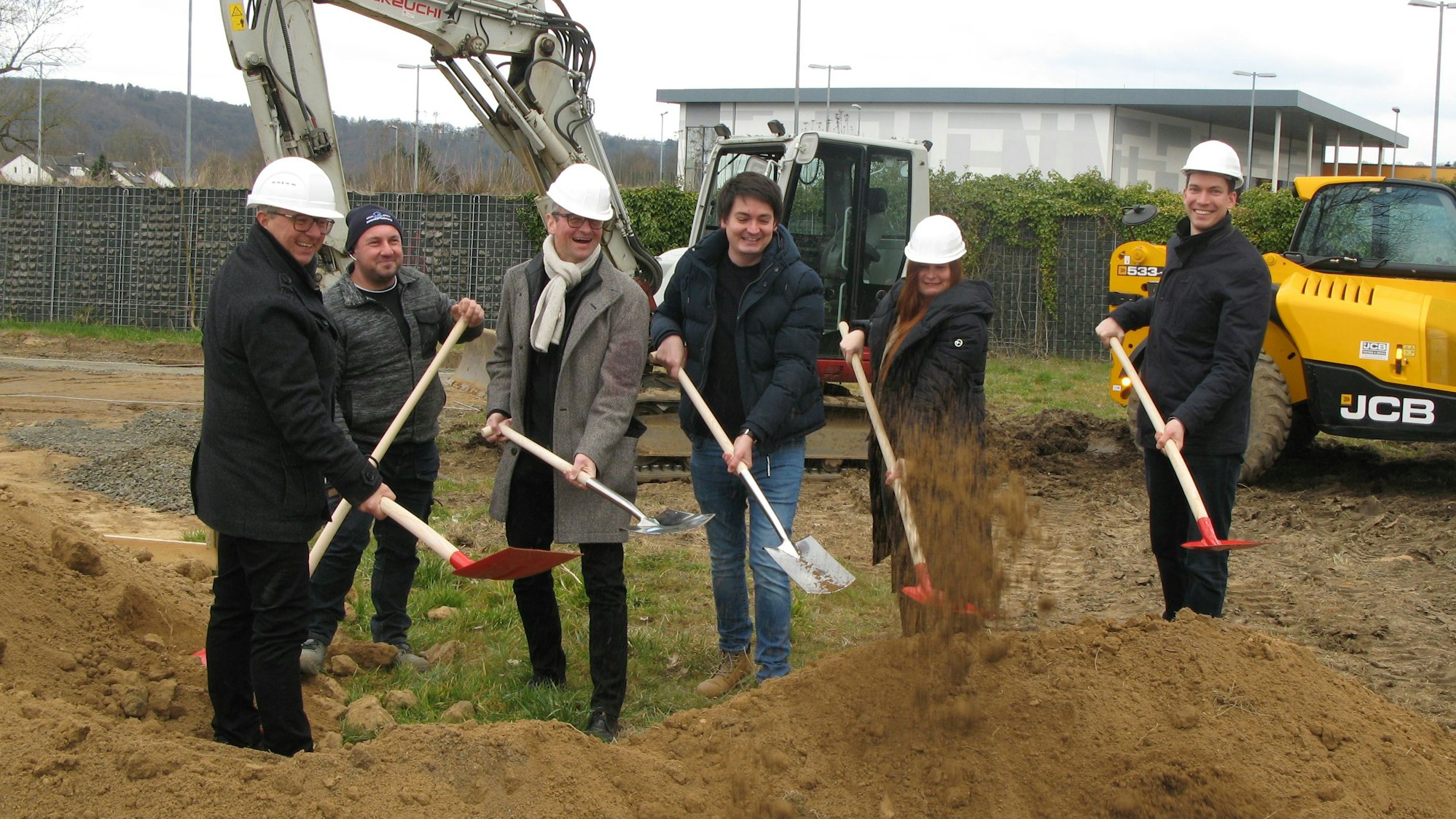 Fünf Männer und eine Frau mit Spaten hinter einem kleinen Erdwall.