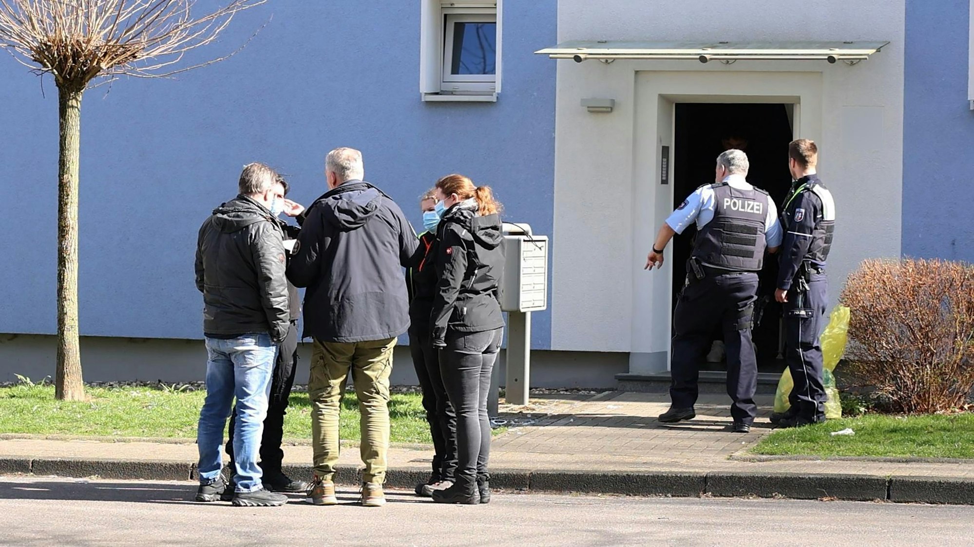 17.03.2025, Herne: Mehrere Personen und Polizei stehen vor einem Hauseingang. Die Polizei hat in Herne einen mutmaßlichen Messerangreifer erschossen. (zu dpa «Polizei erschießt mutmaßlichen Messerangreifer in Herne») Foto: Justin Brosch/dpa - ACHTUNG: Hausummer wurde(n) aus rechtlichen Gründen gepixelt +++ dpa-Bildfunk +++