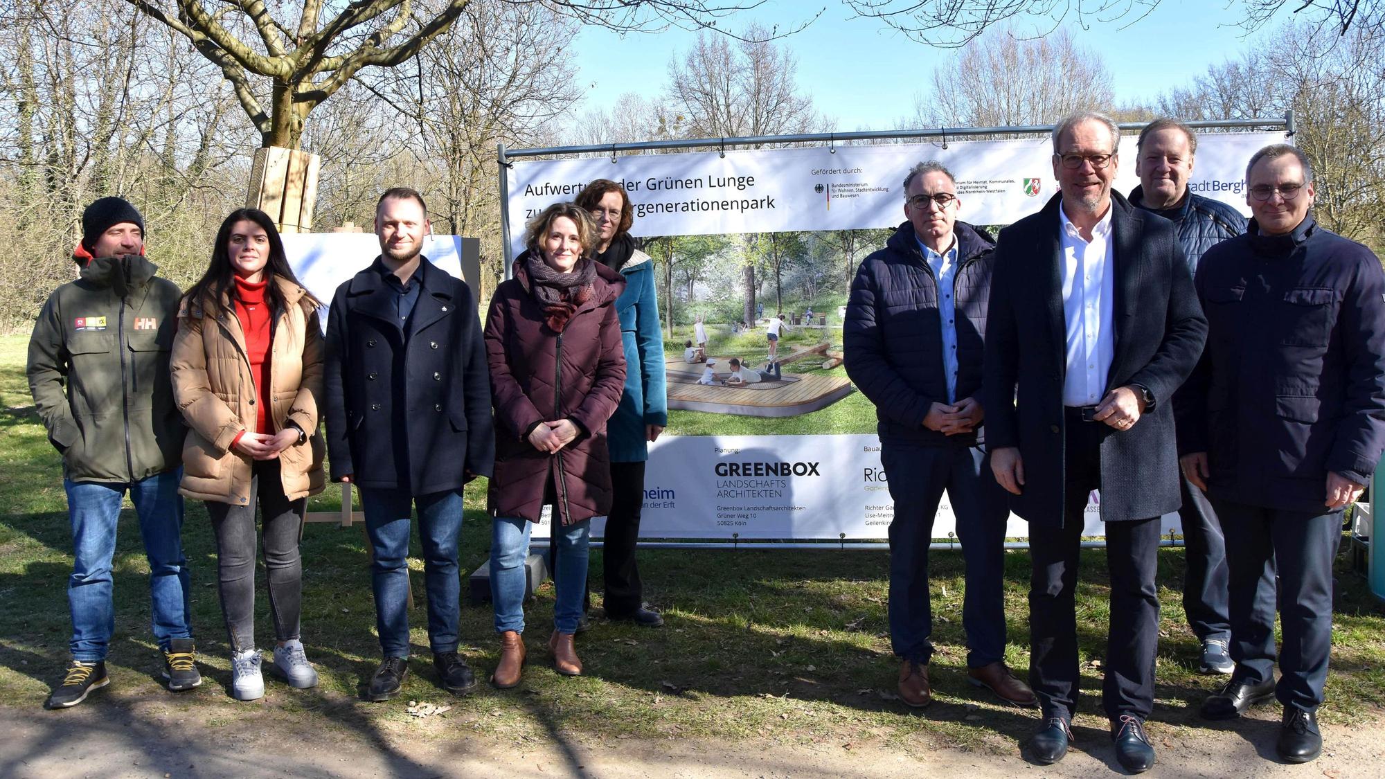 Das Foto zeigt eine Delegation von Menschen vor einem Plakat im Park „Grüne Lunge“.