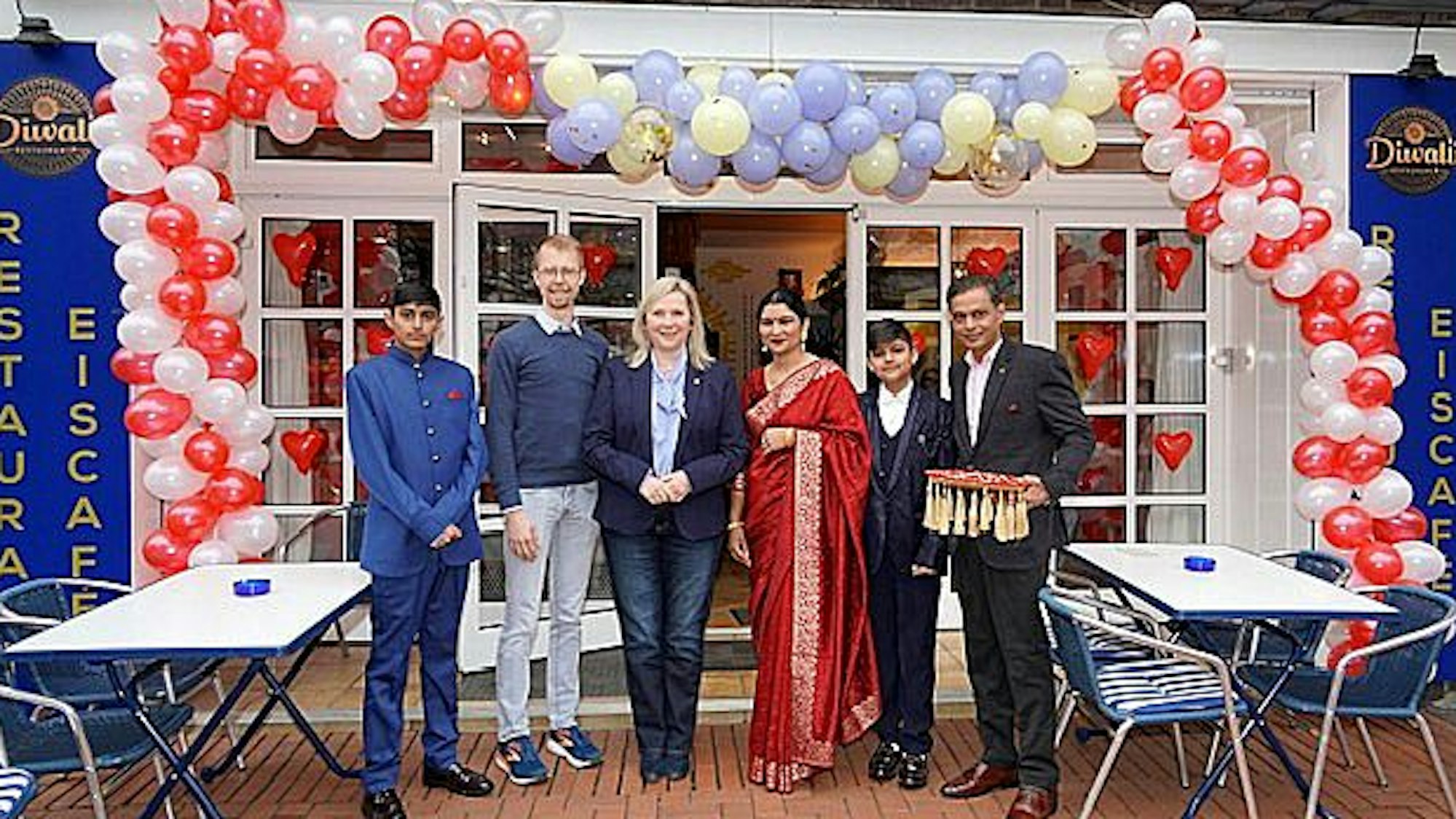 Afu dem Bild ist eine Gruppe von Menschen vor dem Restaurant zu sehen.