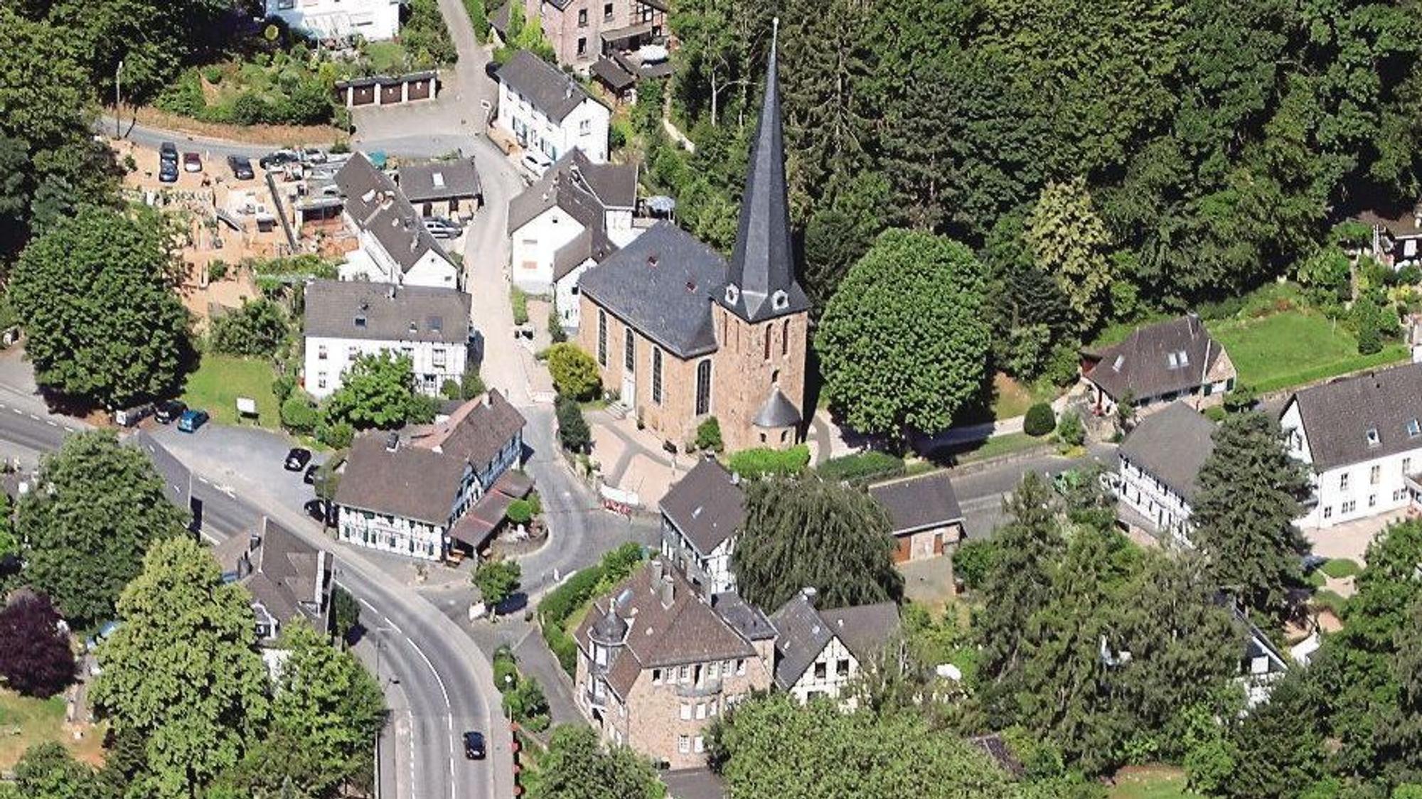 Auf einem Luftbild sind eine Kirche, Fachwerkhäuser, weitere Häuser und Straßen zu sehen.