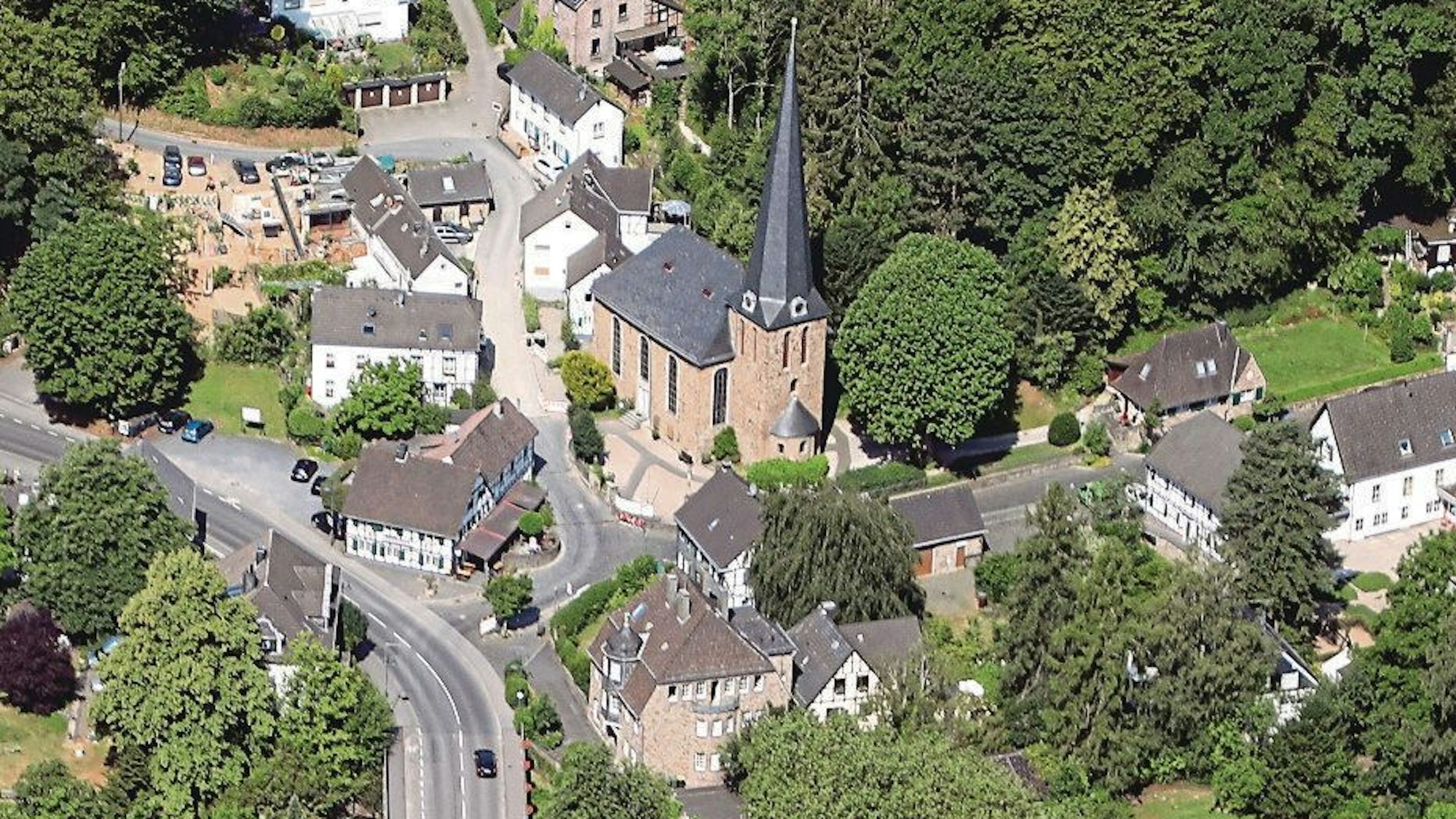 Auf einem Luftbild sind eine Kirche, Fachwerkhäuser, weitere Häuser und Straßen zu sehen.