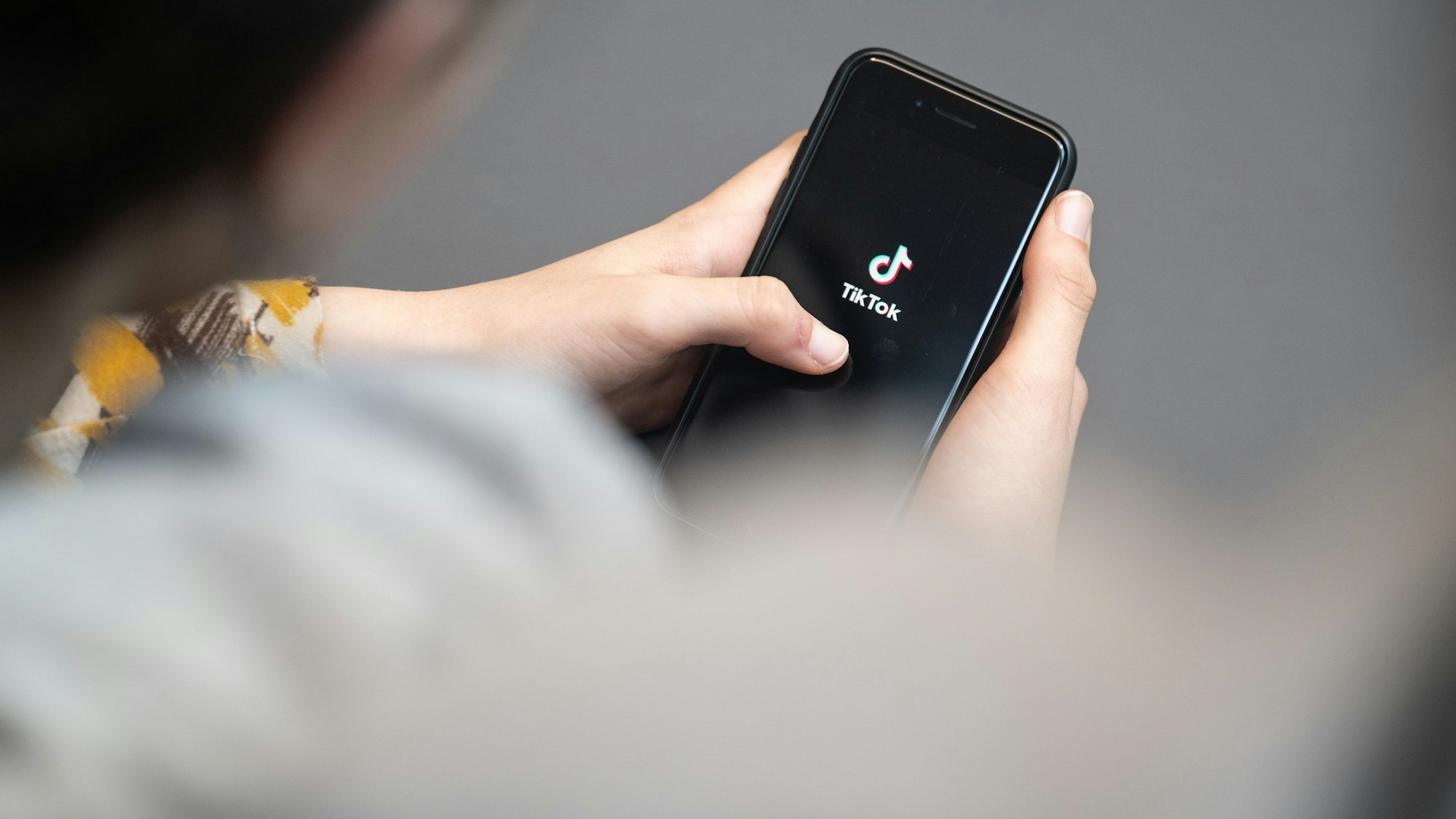 ARCHIV - 25.04.2024, Berlin: Eine Jugendliche schaut auf ein Smartphone mit angezeigtem Tiktok-Logo. (zu dpa: «Umfrage: Junge Menschen denken anders über China») Foto: Hannes P Albert/dpa +++ dpa-Bildfunk +++