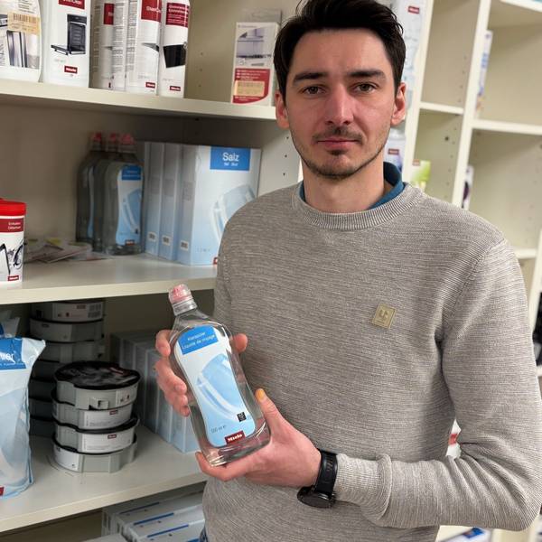 Auf dem Bild ist ein Mann mit einer Flasche Pflegemittel in der Hand zu sehen.