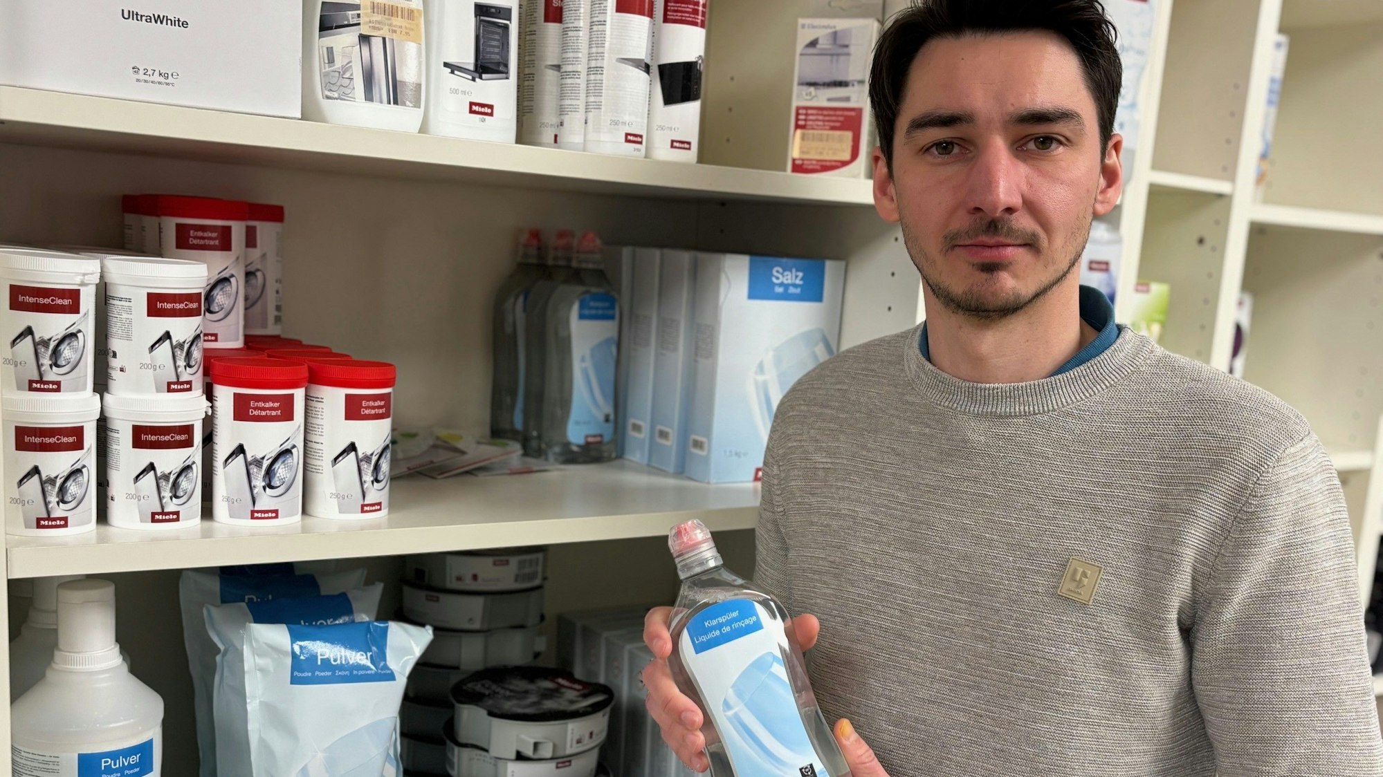 Auf dem Bild ist ein Mann mit einer Flasche Pflegemittel in der Hand zu sehen.