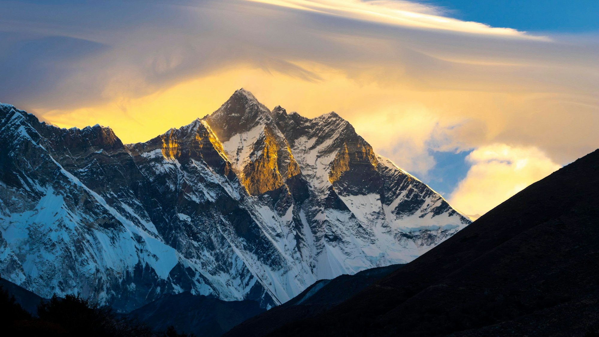 Südwand des Achttausenders Lhotse mit linsenförmigen Wolken über den Gipfeln, bei Sonnenaufgang von Pangboche aus gesehen.