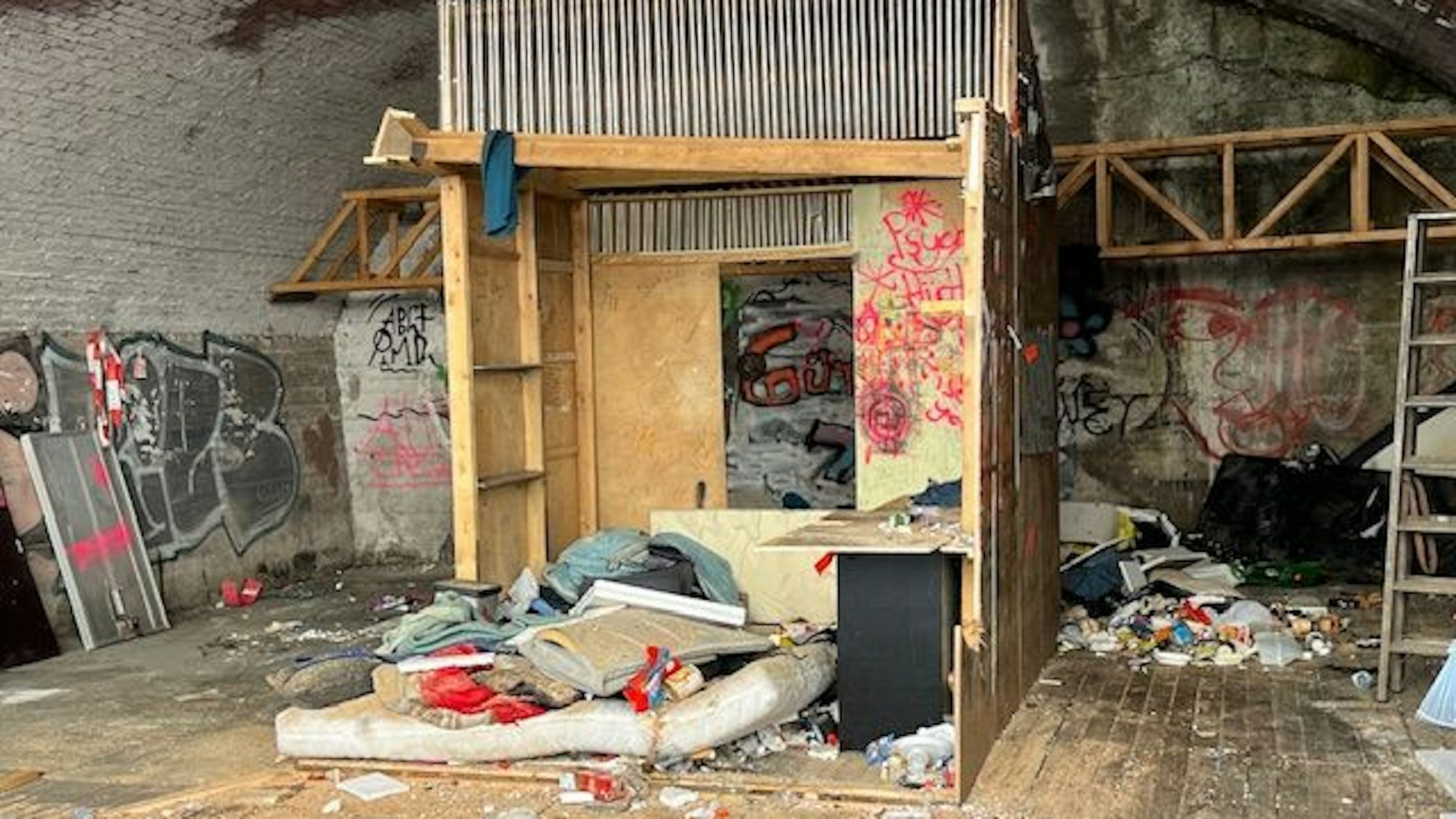 Noch nicht geräumter Bogen an der Hüttenstraße: Zu sehen sind Holzbauten, eine alte Matratze und Abfälle