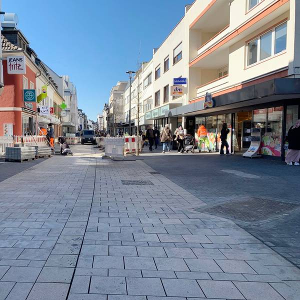 Das Foto zeigt die Fußgängerzone mit frisch verlegtem Pflaster, im Hintergrund Bauzäune, Arbeiter und Passanten.