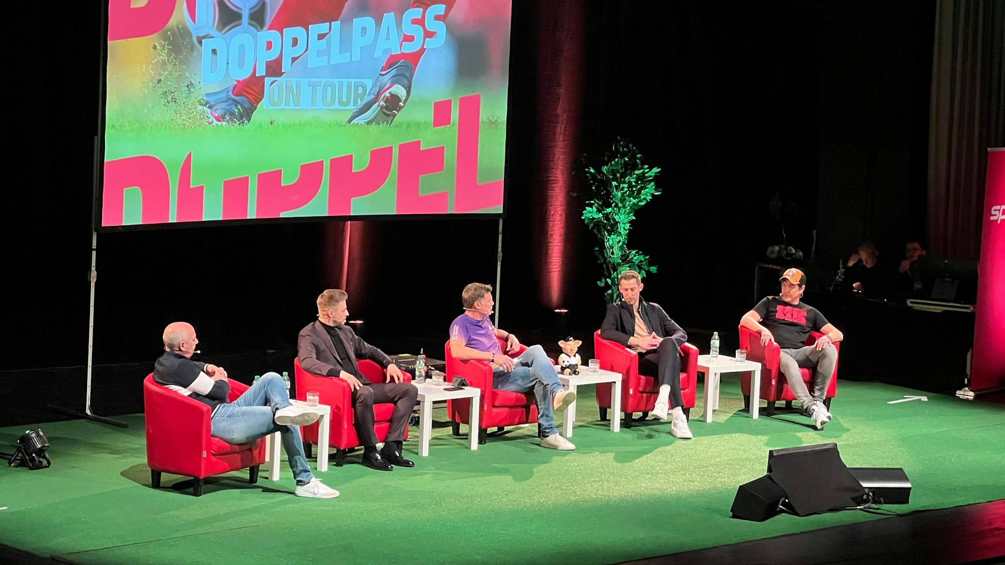 Fünf Männer sitzen auf einem Podium.