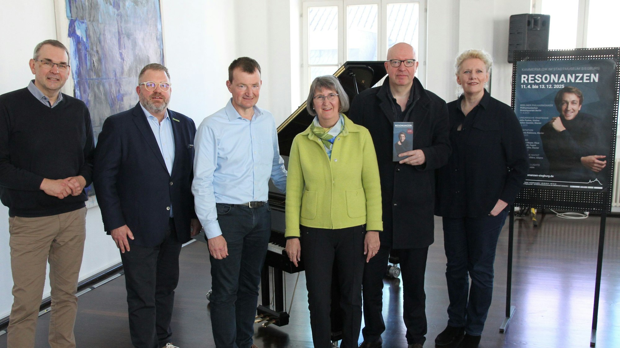 Vier Männer und zwei Frauen vor einem Klavier