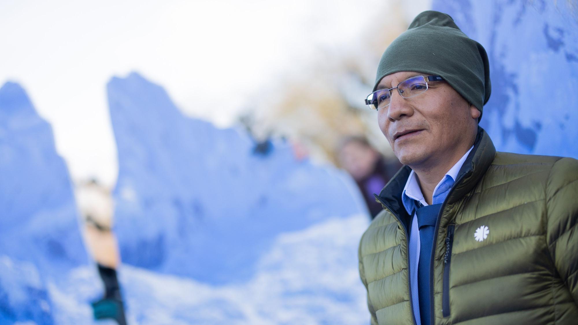 Der peruanische Bergbauer und Bergführer Saul Luciano Lliuya steht vor einem Berg-Bild.