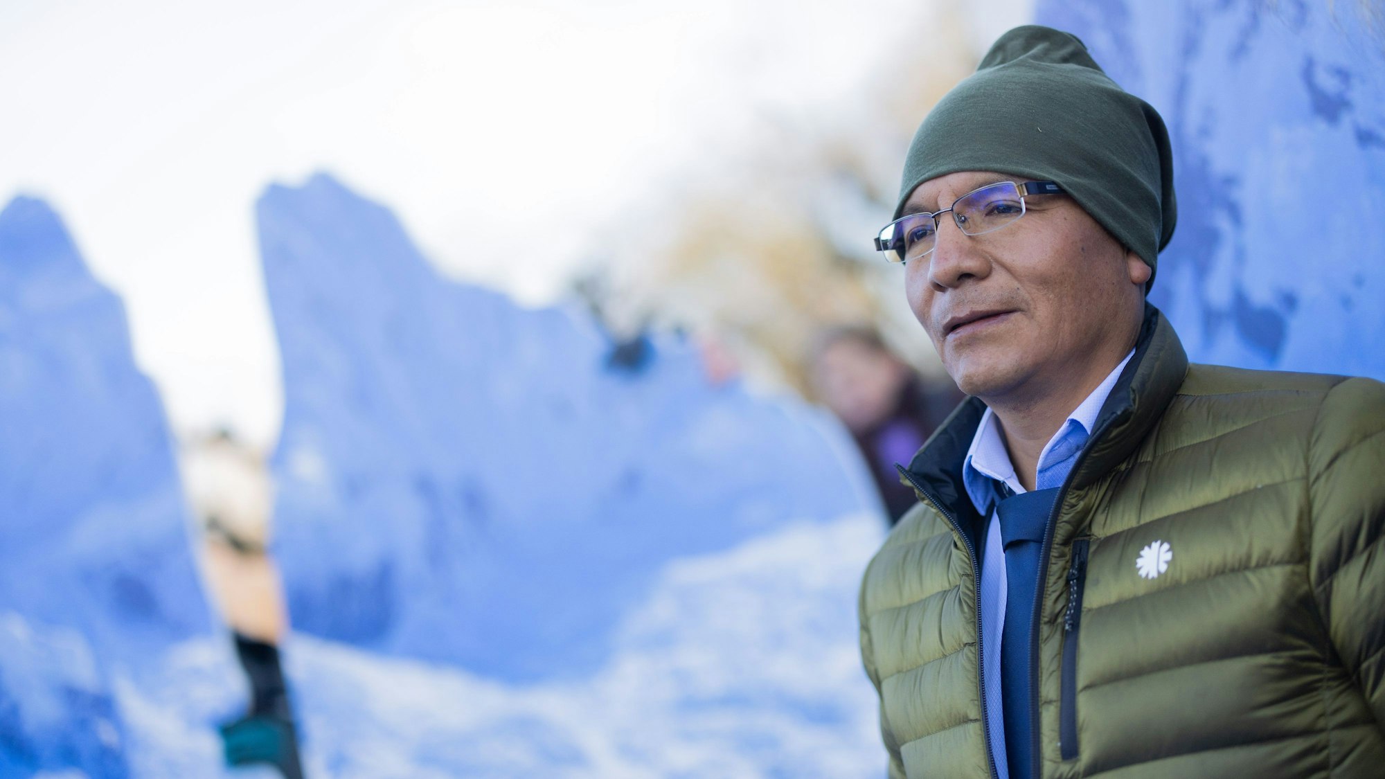 Der peruanische Bergbauer und Bergführer Saul Luciano Lliuya steht vor einem Berg-Bild.