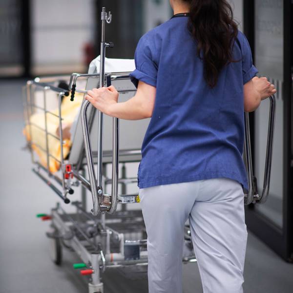 Eine Krankenpflegerin schiebt einen Patienten in einen Krankenhausflur.