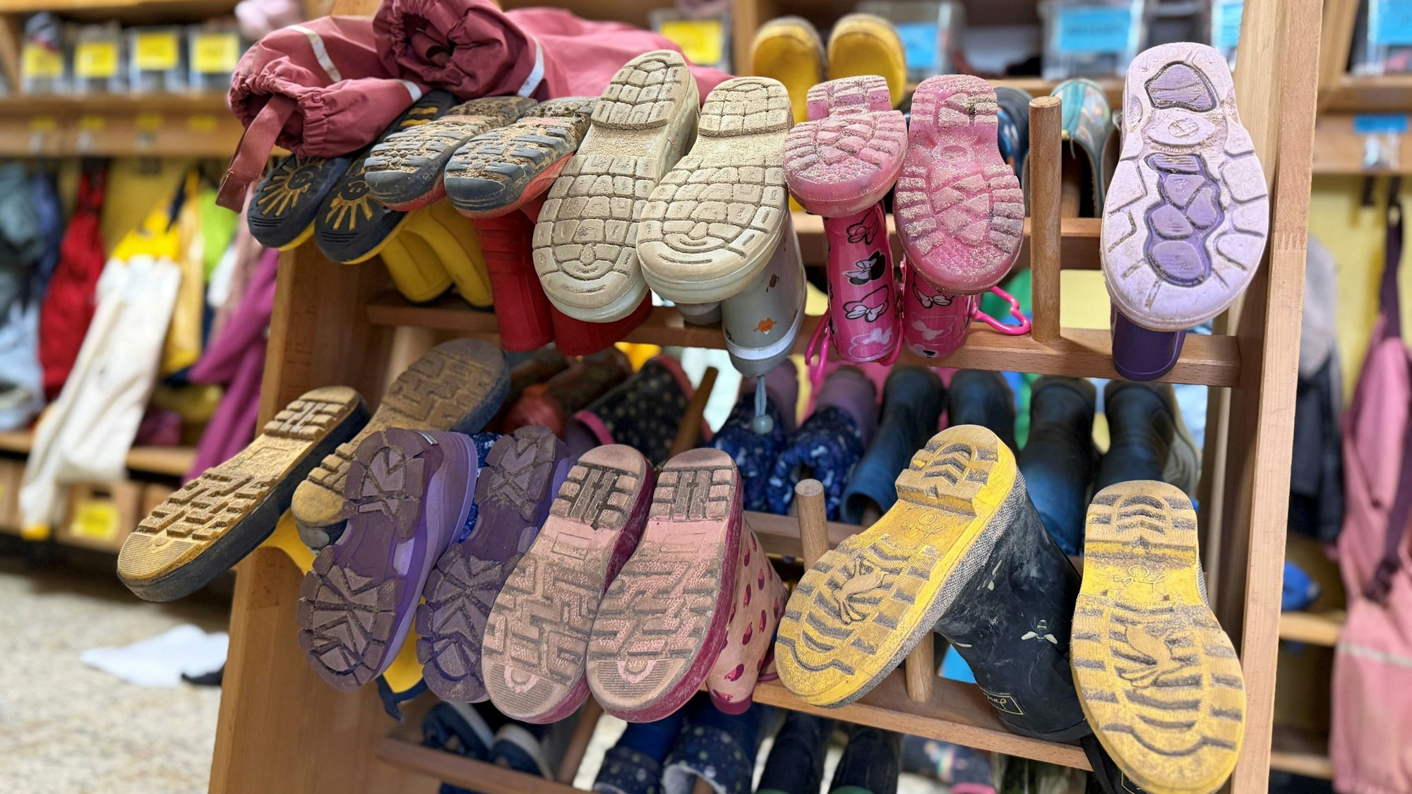 Gummistiefel von Kindern befinden sich in einem rollbaren Ständer, der im Eingangsbereich eines Kindergartens steht.