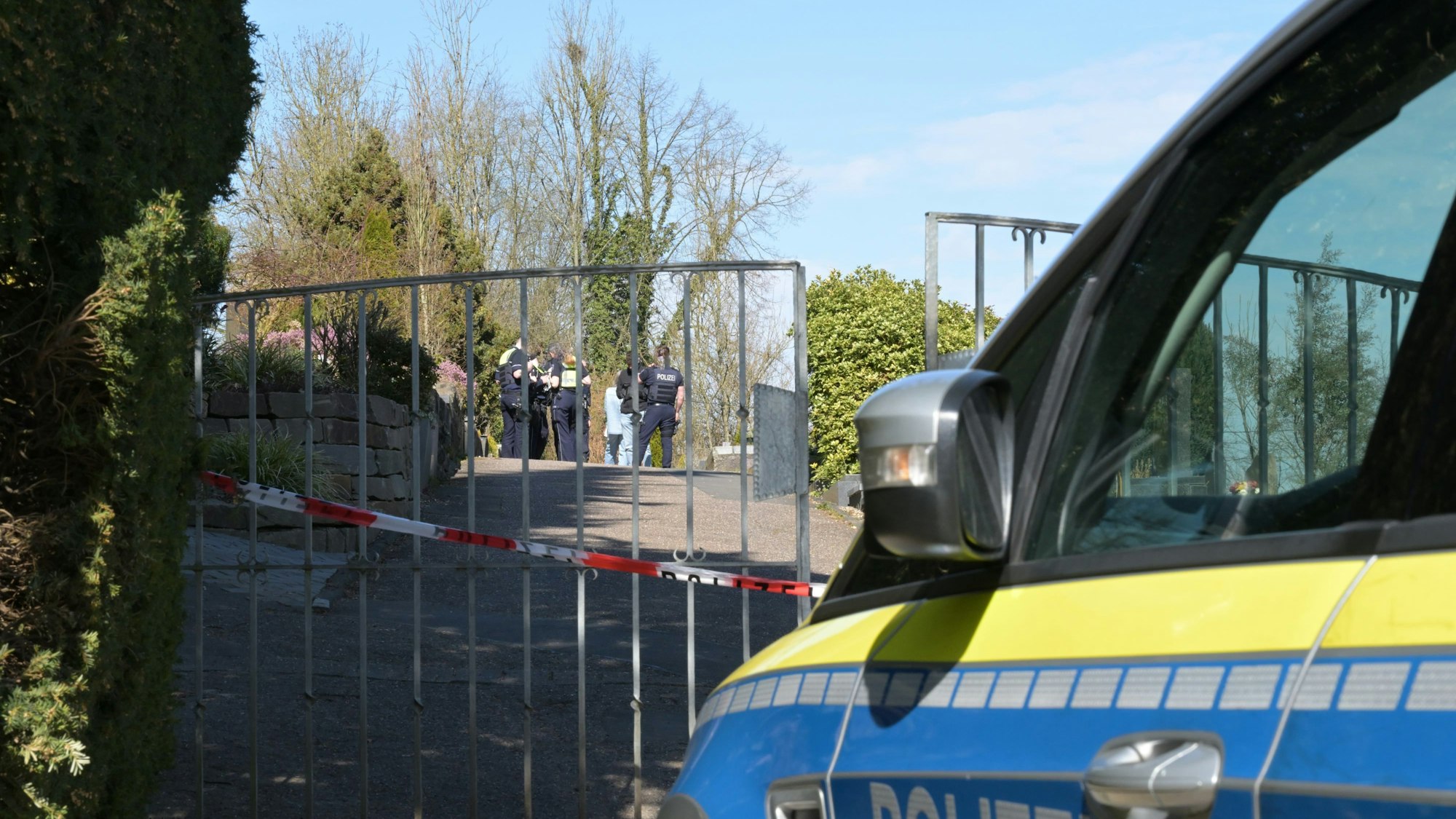 Ein Polizeiauto steht vor dem abgesperrten Volberger Friedhof.