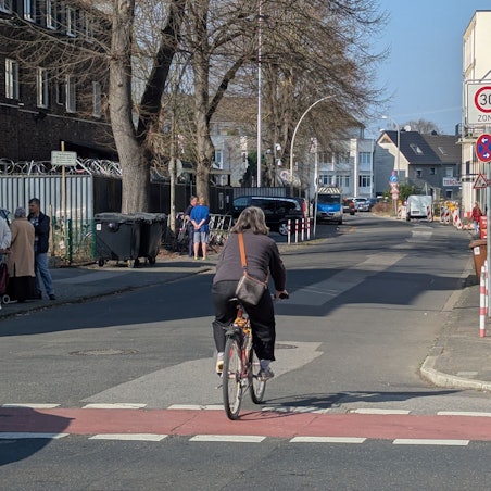 Das Foto zeigt den betroffenen Abschnitt der Kölnstraße, im Vordergrund eine Radfahrerin.