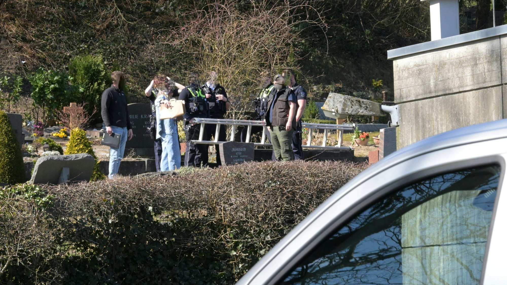 Ermittler der Polizei stehen mit einer Leiter auf dem Volberger Friedhof in Rösrath-Hoffnungtshal.