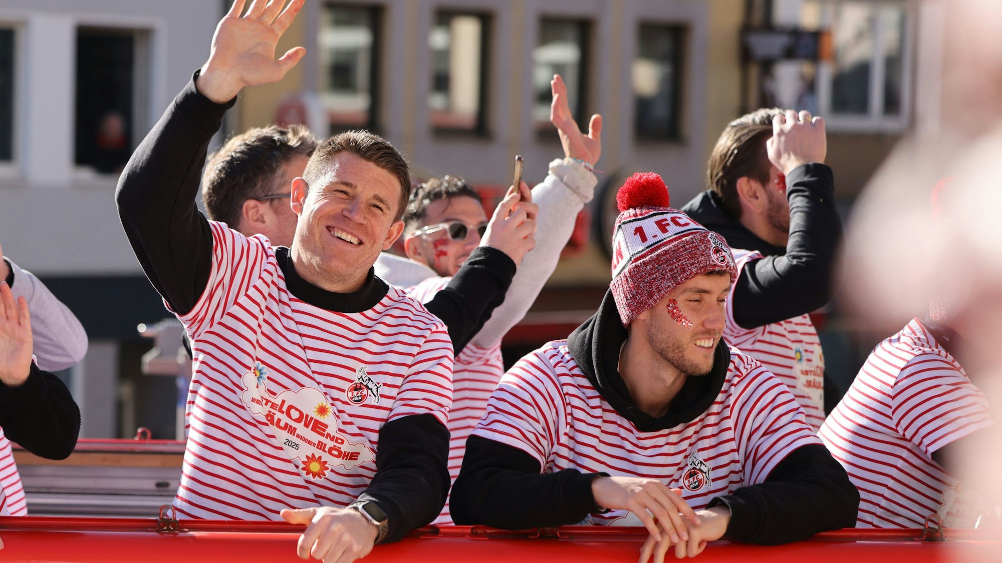 03.03.2025, Nordrhein-Westfalen, Köln: Die Fußballer Dominique Heintz (M) und Luca Waldschmidt (r) fahren auf dem Wagen des 1. FC Köln mit. Mit den Rosenmontagszügen erreicht der rheinische Straßenkarneval seinen Höhepunkt. Das Motto der Kölner Karnevalssession 2025 lautet «FasteLOVEnd - Wenn Dräum widder blöhe». Foto: Oliver Berg/dpa +++ dpa-Bildfunk +++