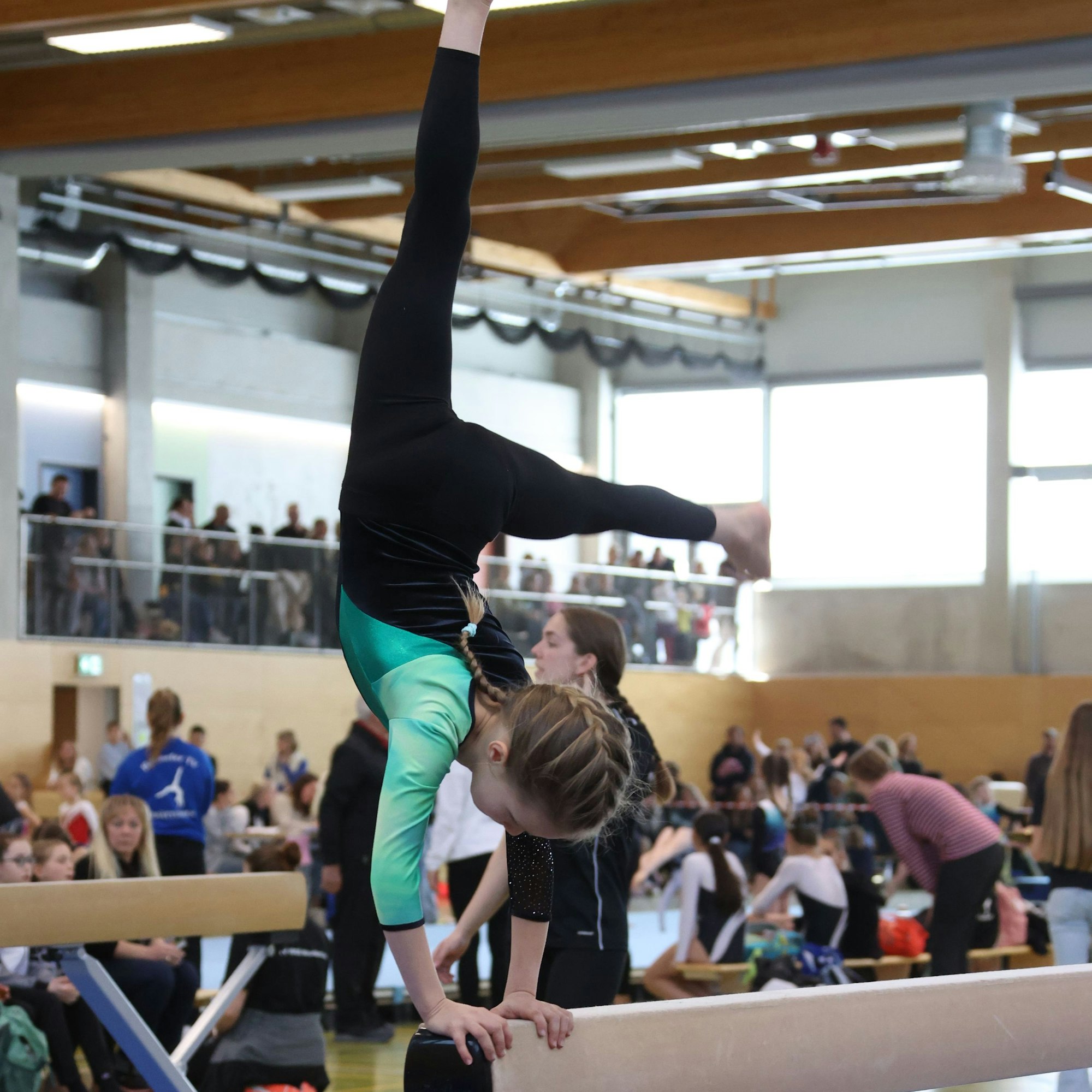 Eine Turnerin steht auf dem Schwebebalken kopf.