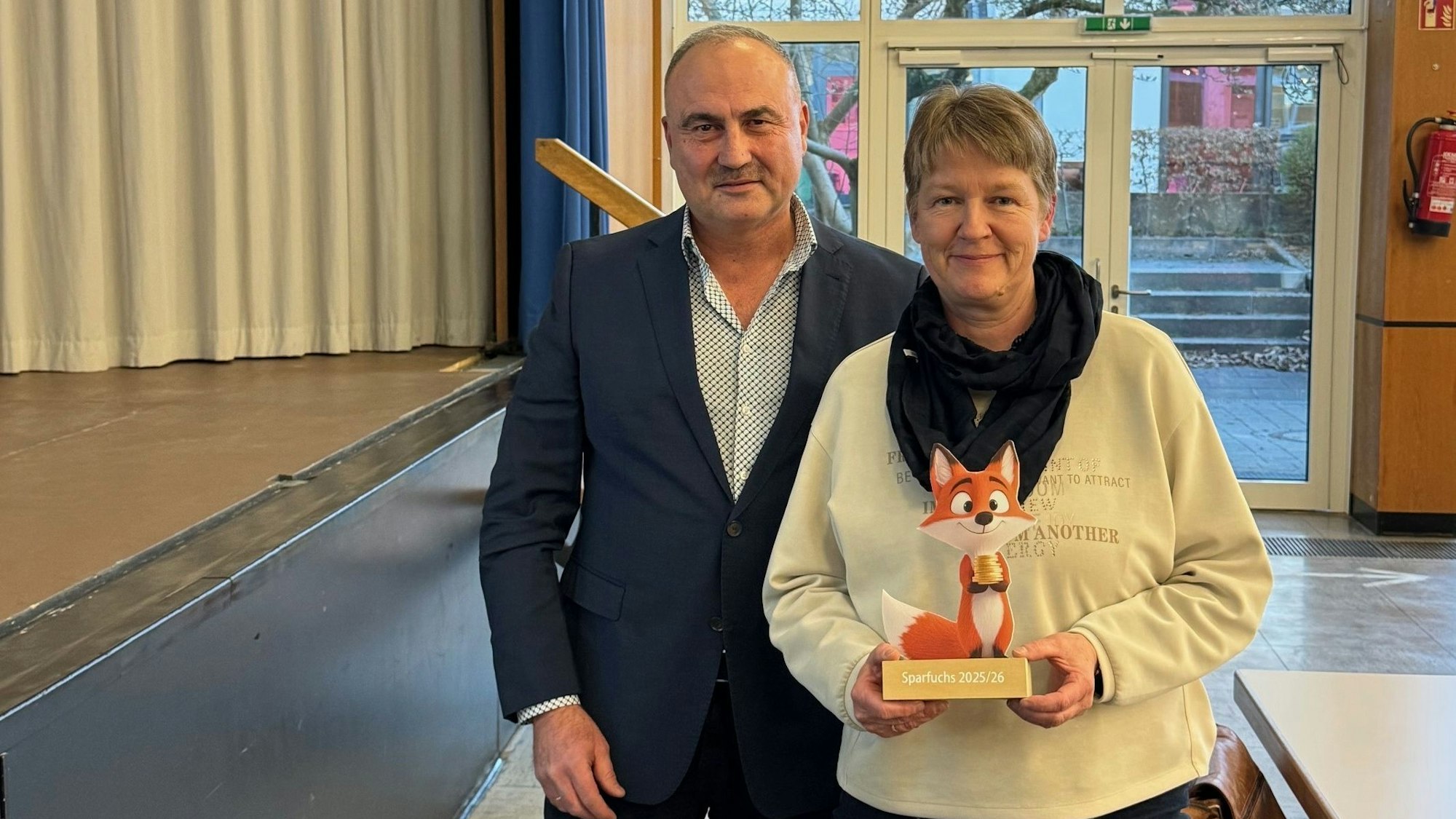 Ein Mann und eine Frau; die Frau hält einen kleinen Pokal in der Form eines Fuchses in der Hand.