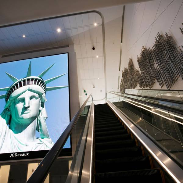 Ein elektronisches Bildschirmbild der Freiheitsstatue begrüßt ankommende Reisende auf einer Rolltreppe im Terminal B des Flughafens LaGuardia.