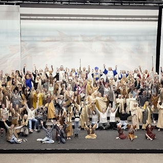 Die Darsteller haben sich in ihren Kostümen zum Gruppenbild auf der Bühne versammelt.