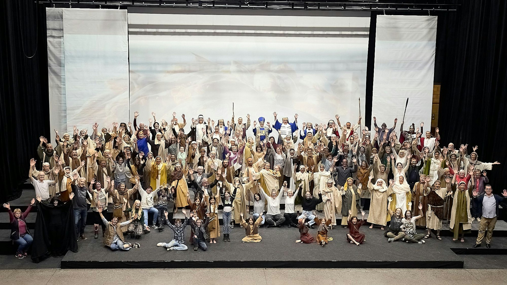 Die Darsteller haben sich in ihren Kostümen zum Gruppenbild auf der Bühne versammelt.