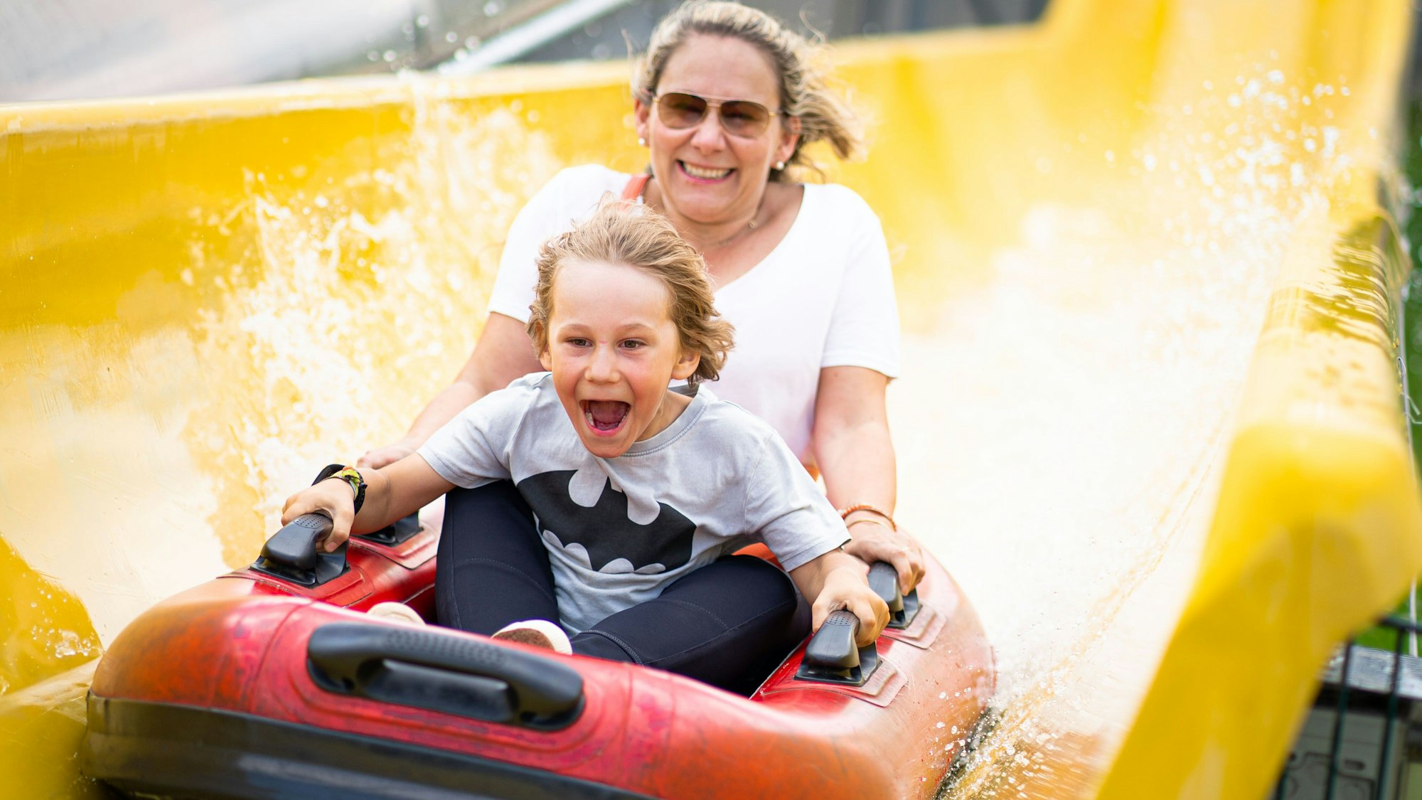Ein Kind und eine Frau sitzen in einem Bötchen in der Wasserrutsche im Bubenheimer Spieleland.
