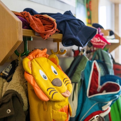 Kinderrucksäcke hängen in einer Garderobe einer Kita. Foto: Christophe Gateau/dpa
