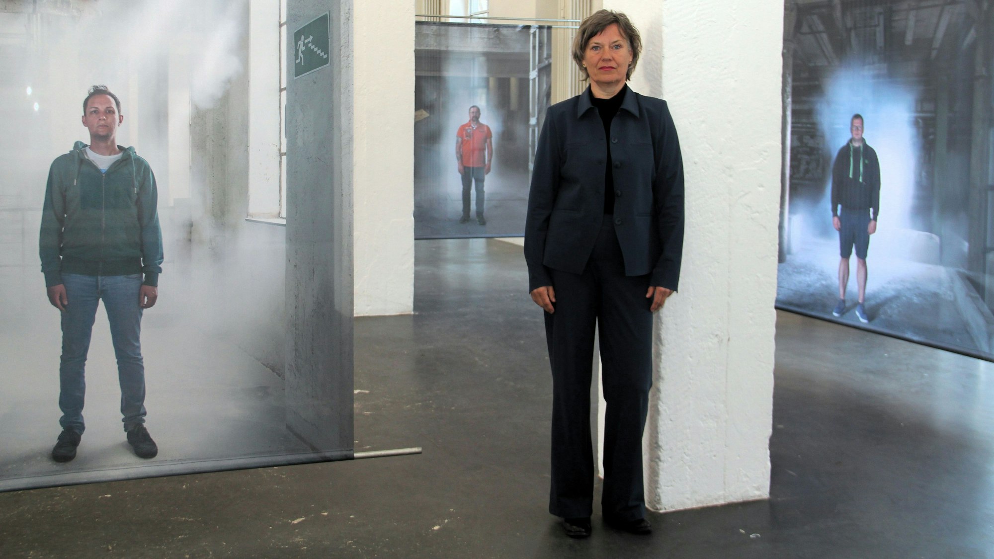 Eine Fotografin steht neben ihren Modellen in der Ausstellung „Aurora“.