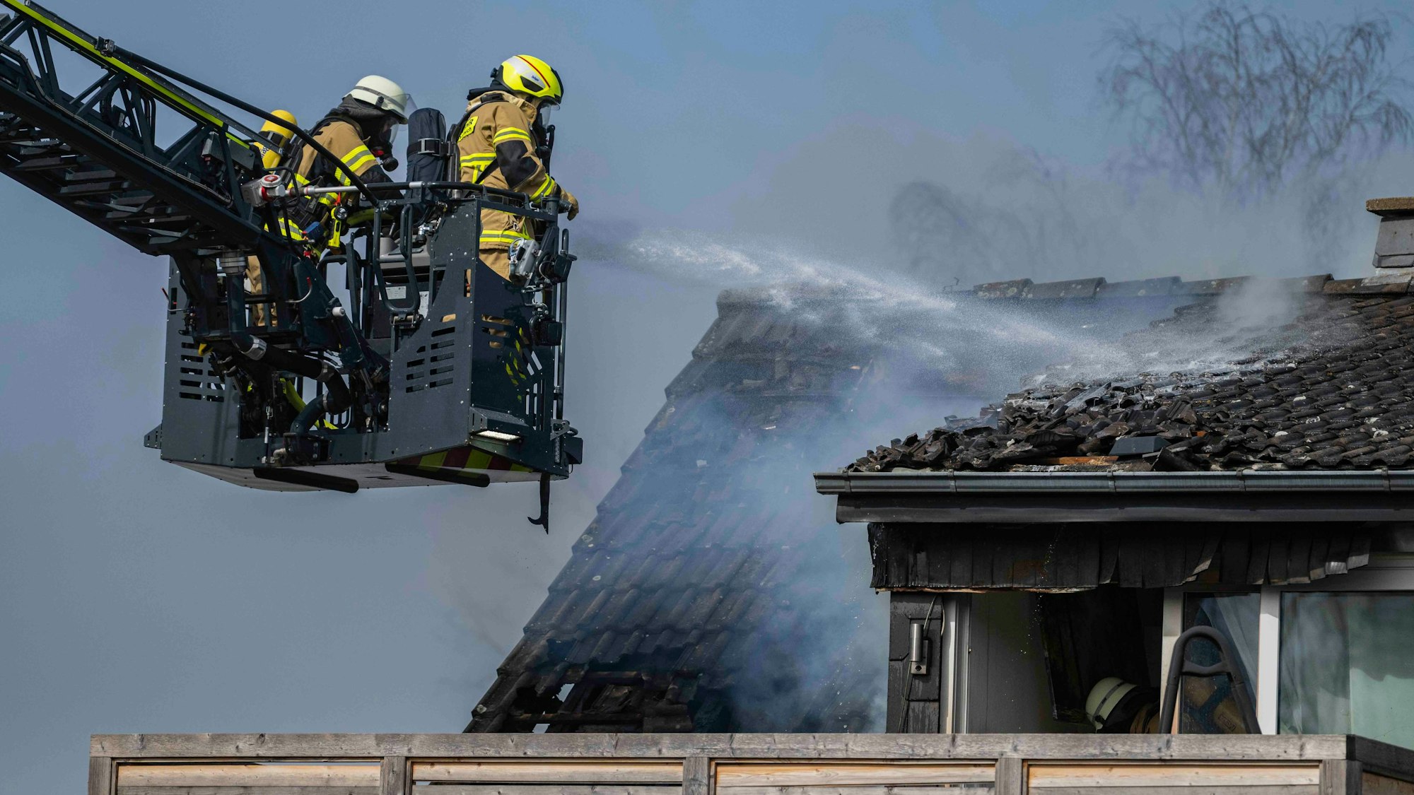 Das Bild zeigt zwei Feuerwehrleute, die vom Korb der Drehleiter aus das Feuer bekämpfen.
