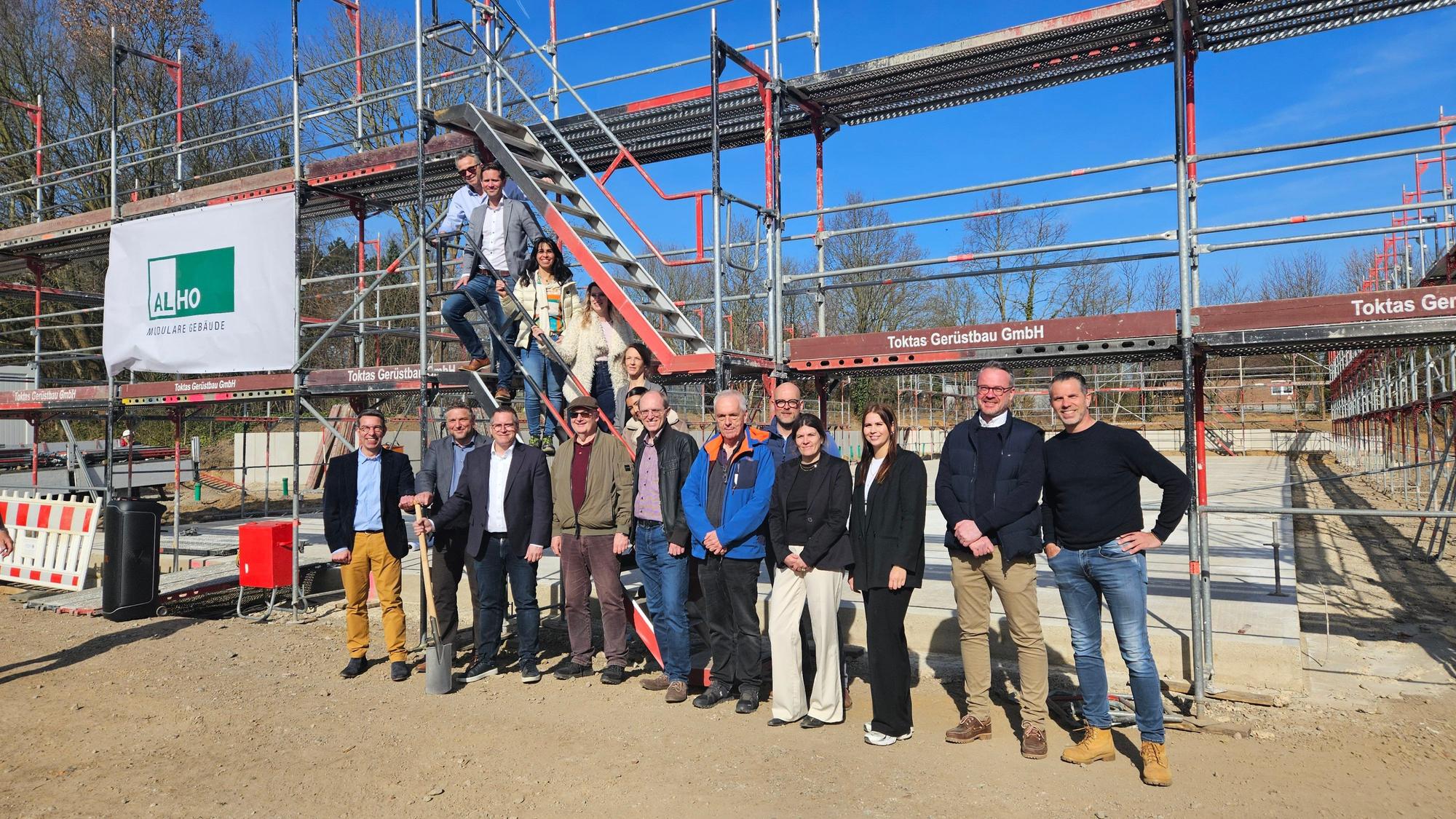 Zu sehen sind zahlreiche Menschen auf einer Baustelle für einen Kindergarten in Bedburg.