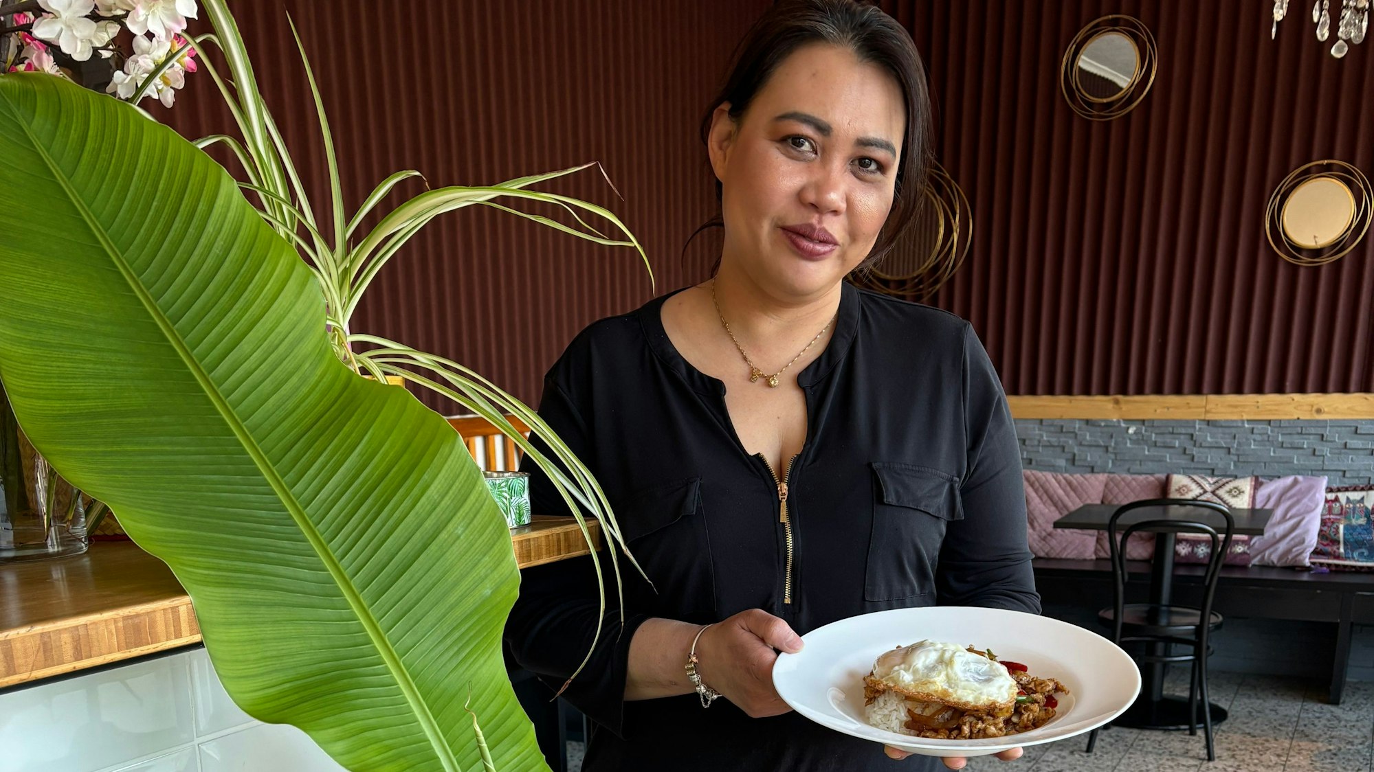 Das Foto zeigt eine Frau, die einen Teller mit einer Mahlzeit in die Kamera zeigt.