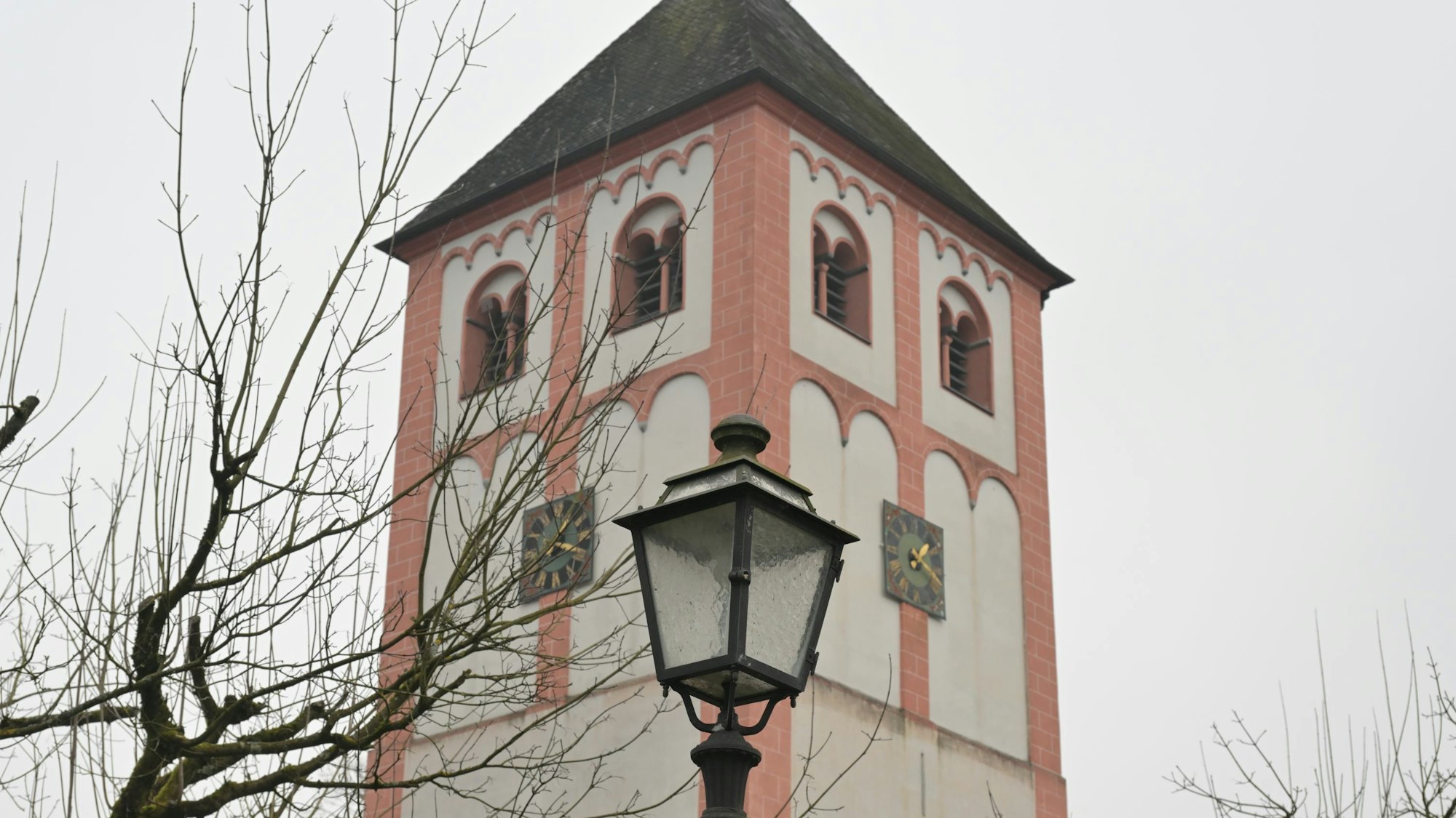 Ein romanischer Kirchturm, davor eine historische Laterne