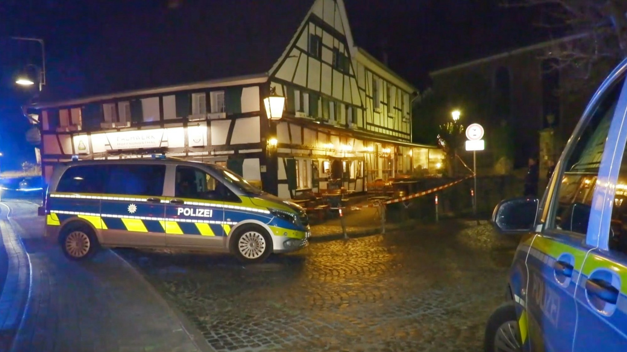 Polizeifahrzeuge stehen in der Nacht vor der Gaststätte Fachwerk in Rösrath-Hoffnungsthal.
