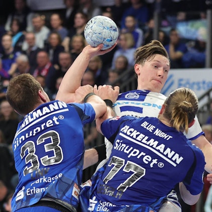 Ole Pregler beim Wurf, den die Erlanger Maciej Gebala (77) und Nikolai Link (33) verhindern wollen.