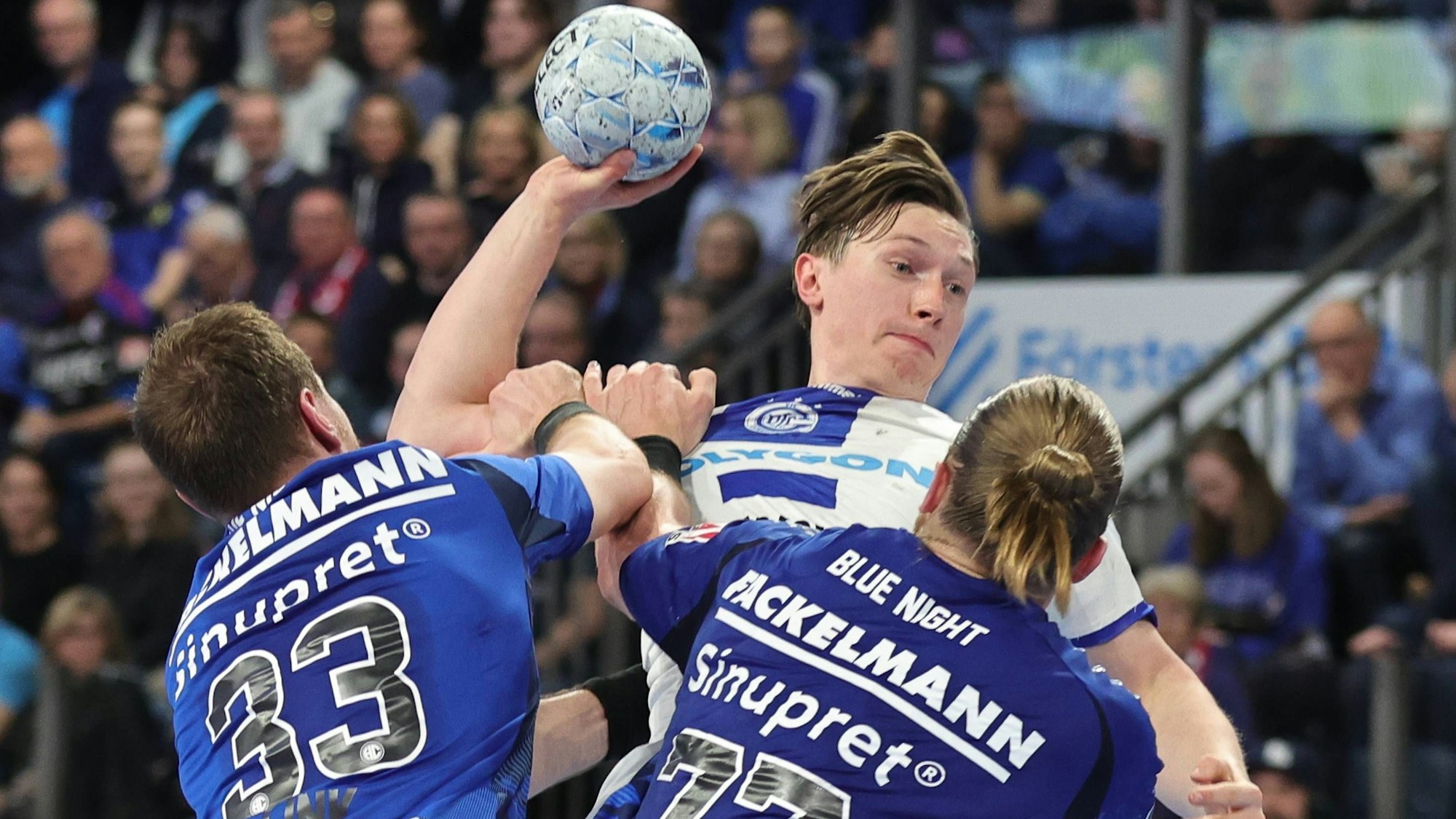 Ole Pregler beim Wurf, den die Erlanger Maciej Gebala (77) und Nikolai Link (33) verhindern wollen.